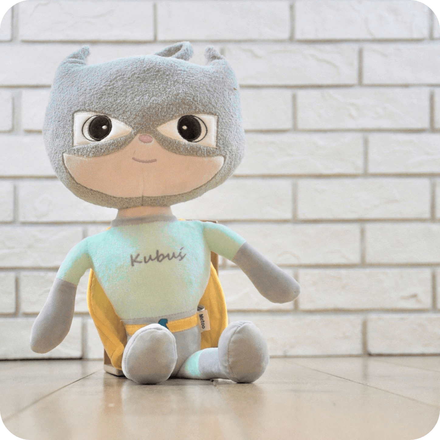 Lalka Metoo Superbohater z maską i żółtą peleryną siedzi na podłodze. Najlepszy prezent z okazji narodzin dla chłopca.