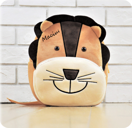 Pluszowy plecak z imieniem dziecka Maciuś. Jest w kształcie lwa i uśmiecha się.